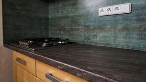 A kitchen with a dark countertop, wooden cabinets, and a backsplash. - Harrachov Pool & Garden by Interhome (Harrachov)