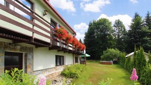 A two-story building with a balcony, surrounded by a well-maintained garden with various plants and flowers. - Harrachov Pool & Garden by Interhome (Harrachov)