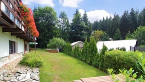 A well-maintained garden with a stone wall, a wooden bench, and neatly trimmed hedges. - Harrachov Pool & Garden by Interhome (Harrachov)
