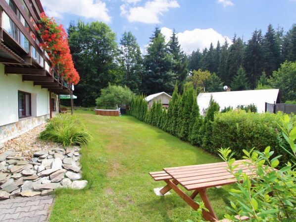 Ein gepflegter Garten mit einer Steinmauer, einer Holzbank und ordentlich geschnittenen Hecken.