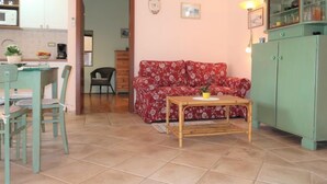 A living room with a red floral sofa, a wooden coffee table, and a green cabinet. - Vacation home Milva by Interhome (Pula/Rakalj)