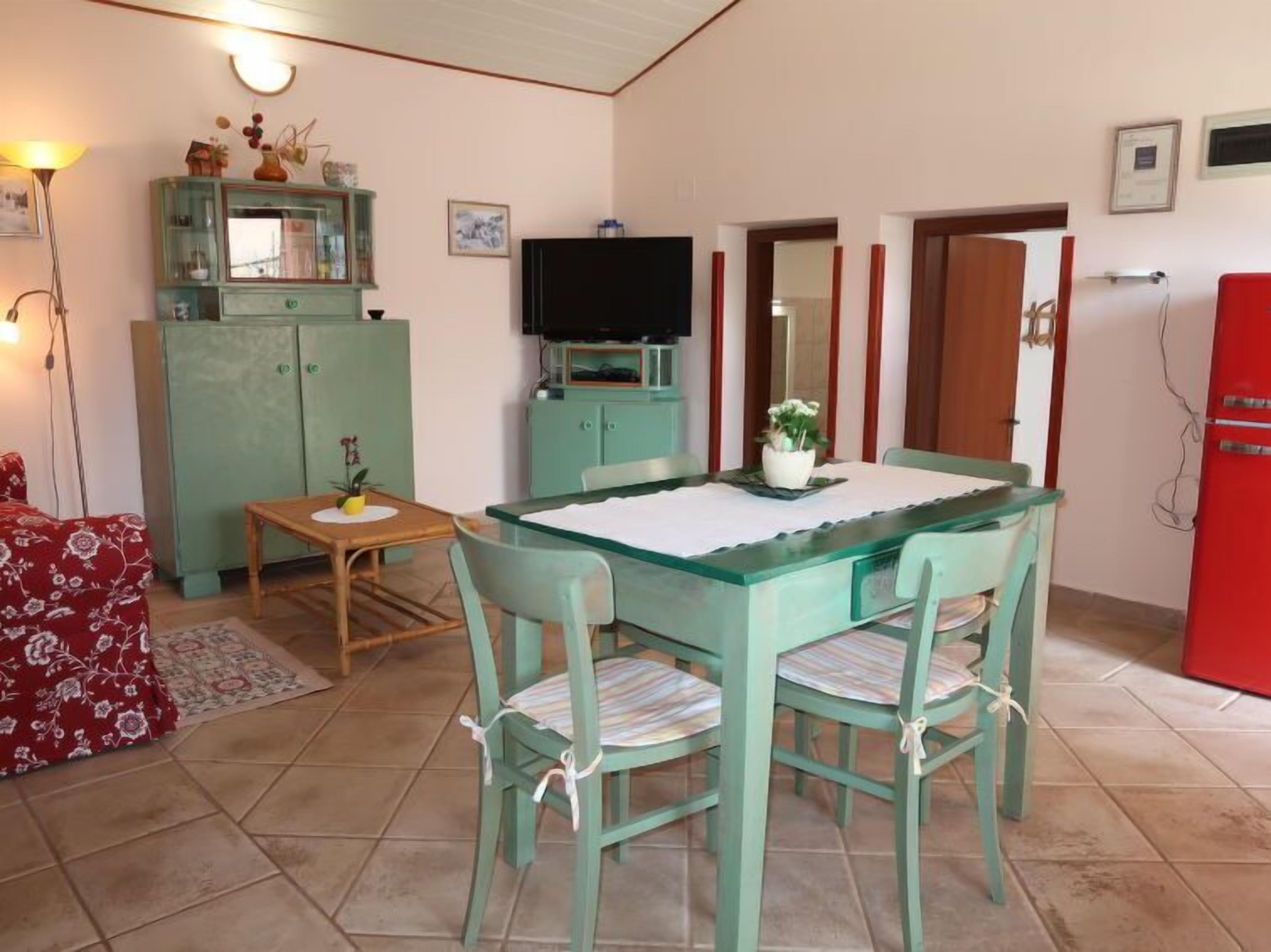 Uma área de refeições com mesa, cadeiras, televisão e um armário.