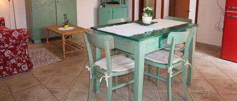 Uma área de refeições com mesa, cadeiras, televisão e um armário.