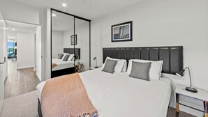 A modern bedroom with a large bed, a ceiling fan, a bedside table with a lamp, and a framed picture on the wall. - Fortitude Valley Apartments By Cllix (Brisbane)