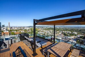 A rooftop terrace with wooden flooring, lounge chairs, and a table. - Fortitude Valley Apartments By Cllix (Brisbane)