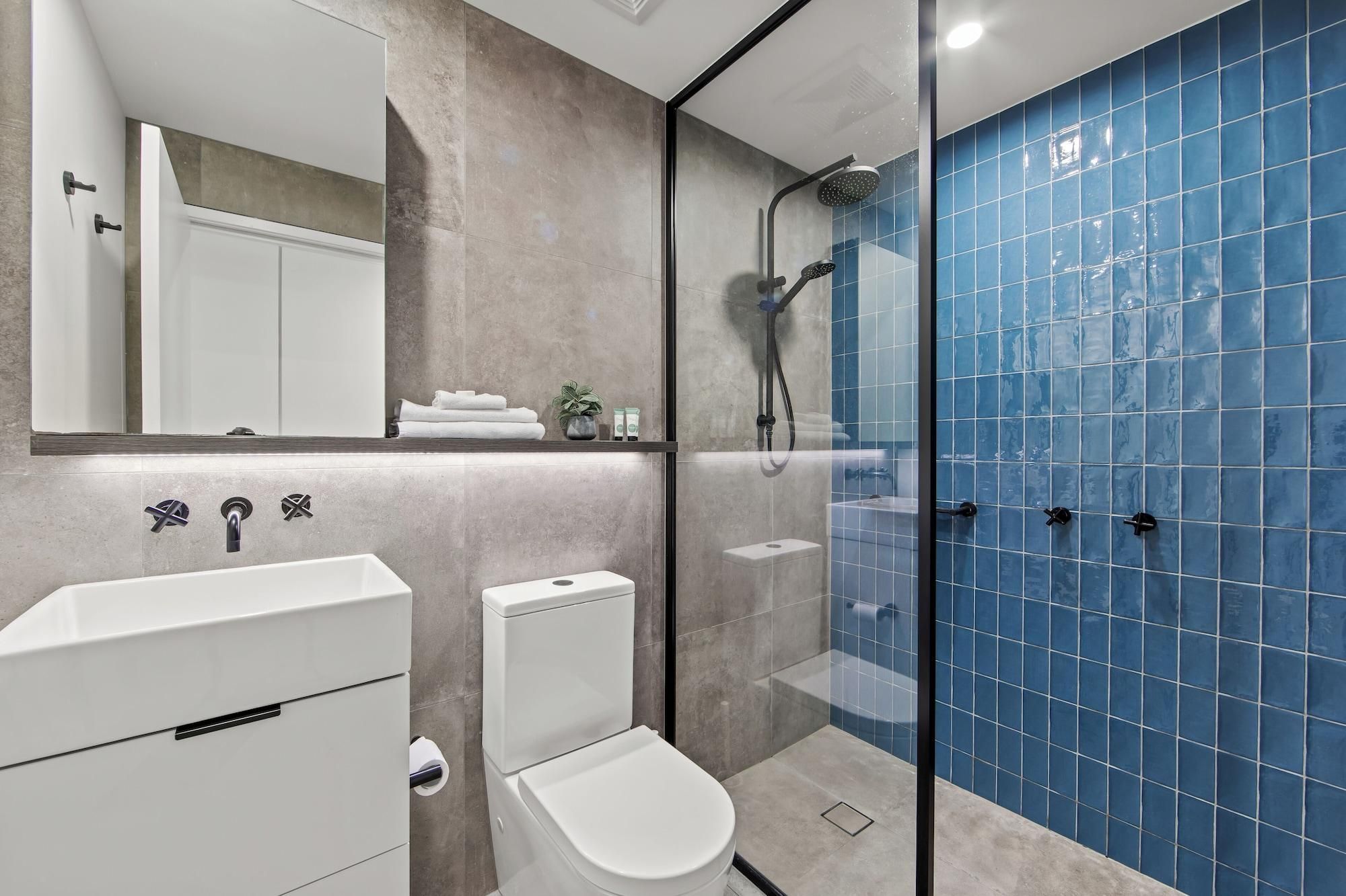 A modern bathroom with a glass-enclosed shower, a white sink, and a toilet.