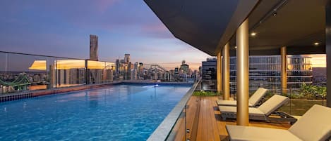 A rooftop pool with lounge chairs, a city skyline view, and a modern architectural design.