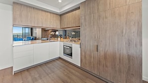 Eine moderne Küche mit Holzschränken, einem Einbauofen und Blick auf die Stadt.
