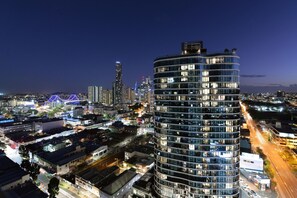 Un immeuble moderne de grande hauteur, avec de nombreux étages, entouré d’un paysage urbain illuminé la nuit.