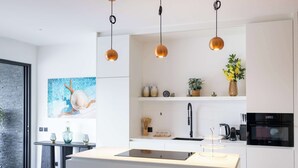 Een moderne keuken met een centraal eiland, hanglampen en een groot raam.