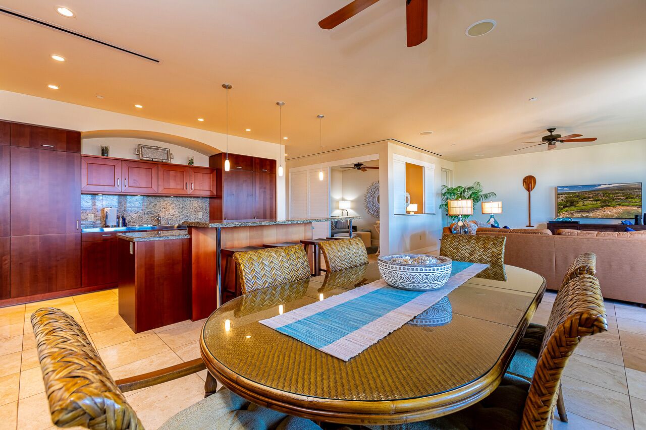 A modern kitchen with dark wooden cabinets, a central island, and pendant lighting.