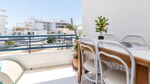 Un balcó amb taula i caires per dinar, i plantes en testos.