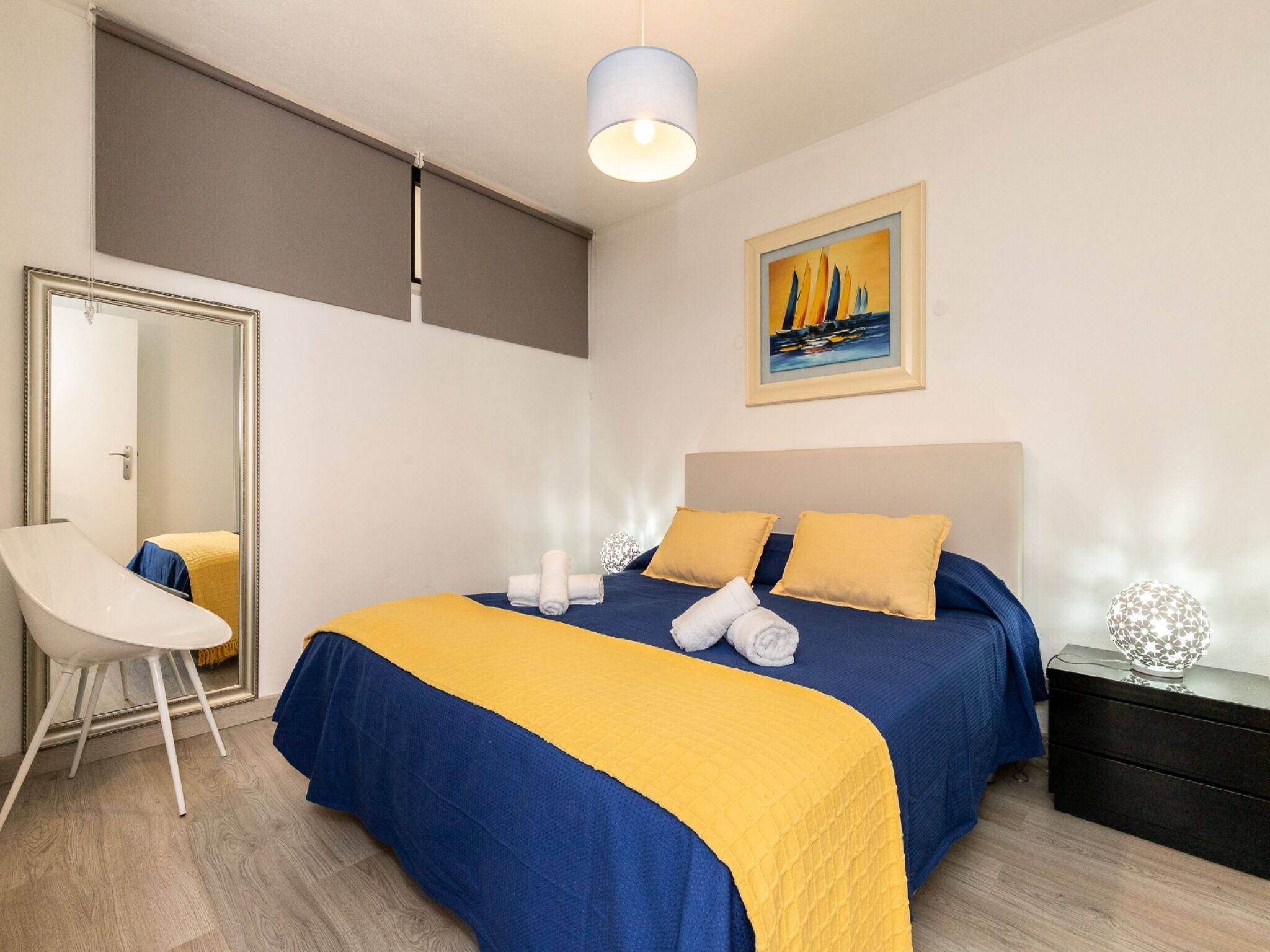 Ein Hotelzimmer mit Bett, Sessel, Nachttisch und einem Bild an der Wand.