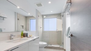 Uma casa de banho moderna com lavatório branco, sanita e área de duche.