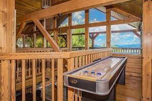 A wooden deck with a foosball table and a view of the outdoors.