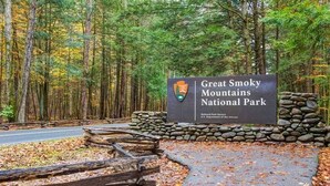 Schild für den Great Smoky Mountains National Park mit einer Steinmauer und Holzzaun.