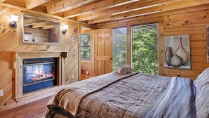 Ein gemütliches Schlafzimmer in einer Holzhütte mit Kamin, Holzwänden und einem Bett mit Decke.