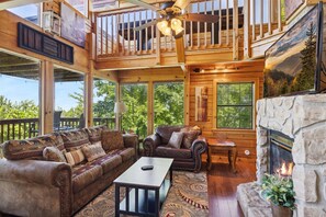 Relax in a spacious living area with a high ceiling, leather sofa, and stone fireplace, offering a comfortable space to unwind.