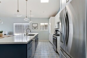 A modern kitchen with a large island, stainless steel appliances, pendant lighting, and a patterned tile floor. - @ Marbella Lane - Home With Majestic Ocean Views (Pacifica)