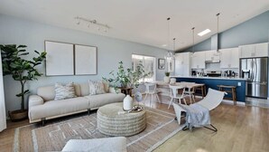 A modern living room with a sofa, ottoman, and chairs, a dining area with a table and chairs, and a kitchen with appliances and cabinets. - @ Marbella Lane - Home With Majestic Ocean Views (Pacifica)