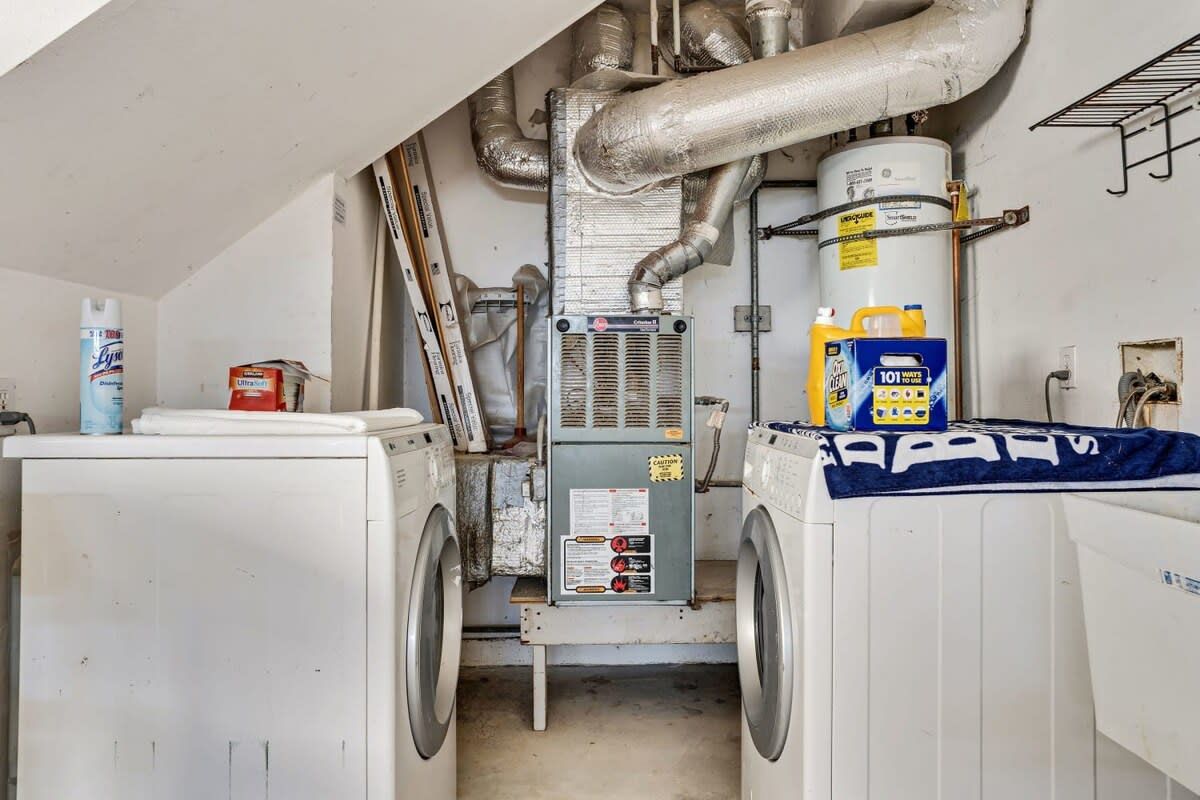 Une buanderie équipée de deux machines à laver, d’un sèche-linge et d’un chauffe-eau.