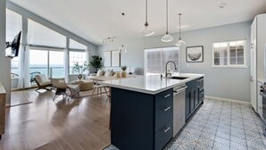 A modern kitchen with a large island, pendant lights, and a view of the sea. - @ Marbella Lane - Home With Majestic Ocean Views (Pacifica)