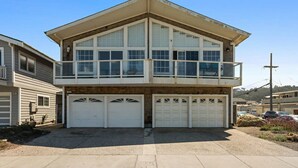 A two-story house with a balcony, two garages, and a driveway.