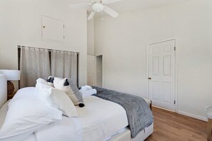 A neatly made bed with white linens and a gray throw blanket, a ceiling fan, and a white door. - @ Marbella Lane - Home With Majestic Ocean Views (Pacifica)