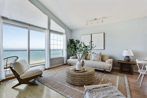 A modern living room with a large window, a sofa, a chair, a coffee table, and a lamp. - @ Marbella Lane - Home With Majestic Ocean Views (Pacifica)