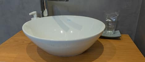 A white ceramic sink with a modern faucet on a wooden countertop.