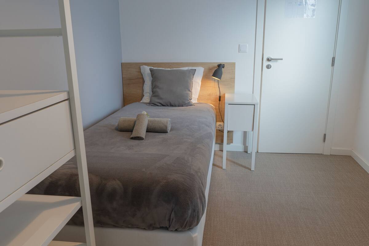 A neatly arranged bedroom with a bed, bedside table, and a door.