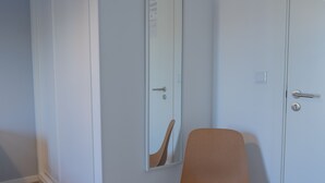 A room with two white doors, one with a mirror reflecting a shoe. A brown chair is positioned in front of the doors. - Solar do Alentejo (Santiago do Cacém)