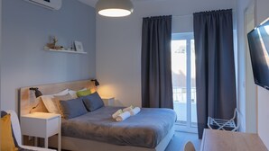 A modern hotel room with a bed, bedside table, lamp, air conditioning unit, and a TV. - Solar do Alentejo (Santiago do Cacém)