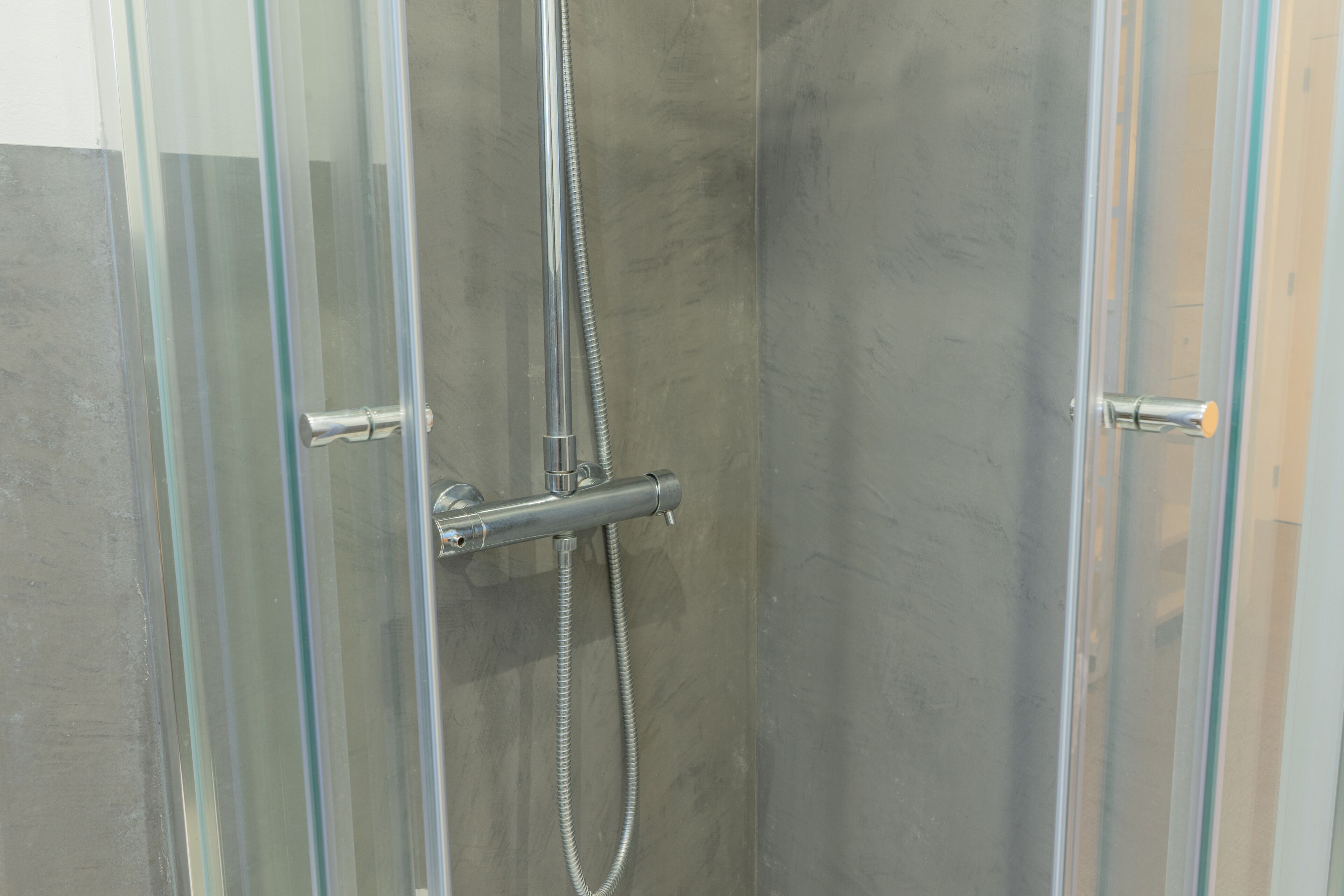 Cabina doccia in vetro con soffione e doccetta cromati.