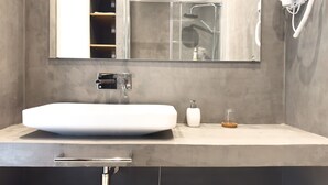 A modern bathroom with a large sink, a mirror, a handheld showerhead, and a hairdryer mounted on the wall. - Solar do Alentejo (Santiago do Cacém)