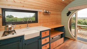 Cocina pequeña con ventana, techo de madera y vistas al exterior.