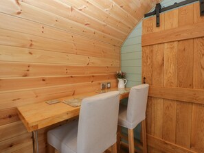 A wooden interior with a table and chairs, a light blue wall, and a wooden door. - Dew Pond (Bristol)