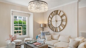 Un salon chaleureux avec une grande horloge murale, un lustre et un canapé confortable.