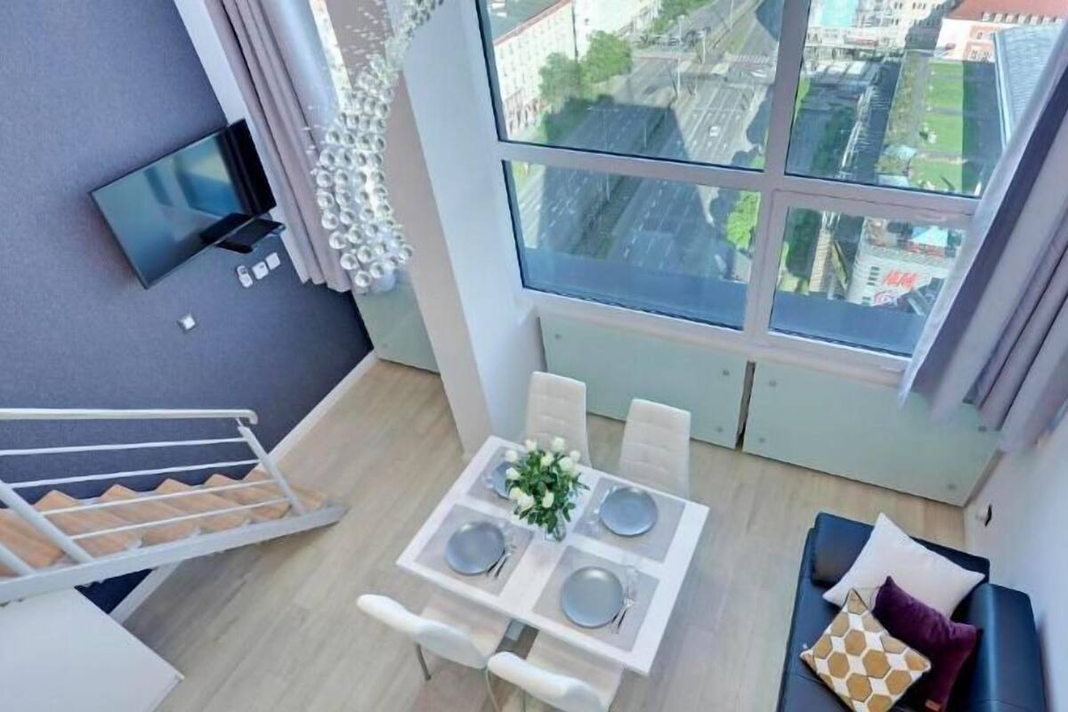 Eine moderne Wohnung mit Essbereich, einem an der Wand befestigten Fernseher und einem großen Fenster mit Blick auf die Stadt.