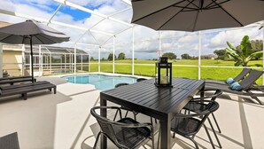 A covered patio with a pool, outdoor furniture, and a view of the surrounding landscape. - This charming 5-bedroom villa with a private heated pool is a modern oasis. (Davenport)