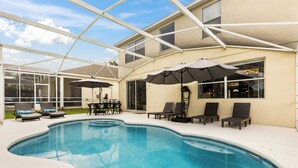 A swimming pool with lounge chairs and umbrellas, surrounded by a covered patio area. - This charming 5-bedroom villa with a private heated pool is a modern oasis. (Davenport)