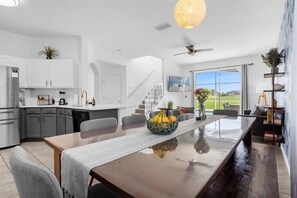Enjoy meals around the central dining table in this stylish space, featuring a kitchen area and comfortable seating.