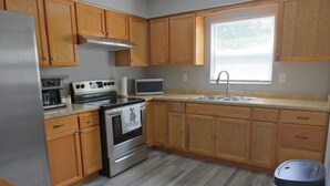 A kitchen with wooden cabinets, a stainless steel refrigerator, a microwave, a stove, and a sink. - Awalk away from Busch Gardens and Adventure Island (Tampa)