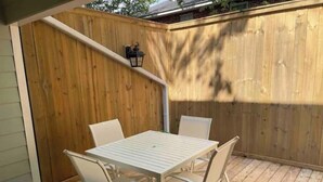 A wooden deck with a white metal table and four chairs. - End unit townhouse (Baton Rouge)