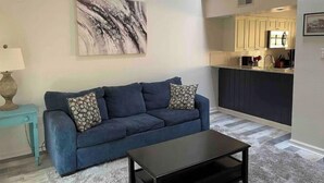 A living room with a blue sofa, a coffee table, and a painting on the wall. - End unit townhouse (Baton Rouge)