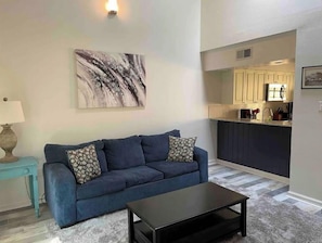 Relax in a stylish living space with a sofa, coffee table, and rug, adjacent to a modern kitchen with a visible island.
