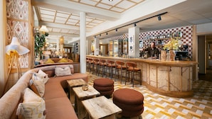 A modern bar area with a checkered floor, wooden bar counter, and seating arrangement. - NH Copenhagen Grand Joanne (Copenhagen)