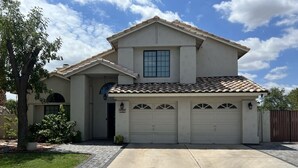 Une maison à deux étages avec un garage, une entrée principale et une allée.