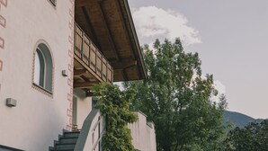A building with a staircase leading to a balcony, surrounded by trees and a mountain in the background. - 164 apt. - Spacious & exclusive appartment with view (Pfitsch)