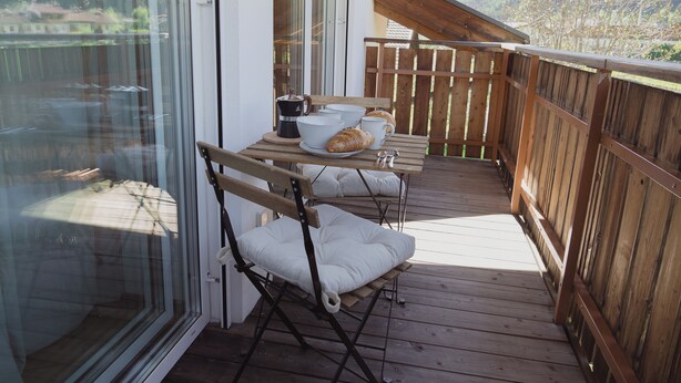 A wooden deck with a table set for breakfast, including a croissant, coffee, and cups. - 164 apt. - Spacious & exclusive appartment with view (Pfitsch)